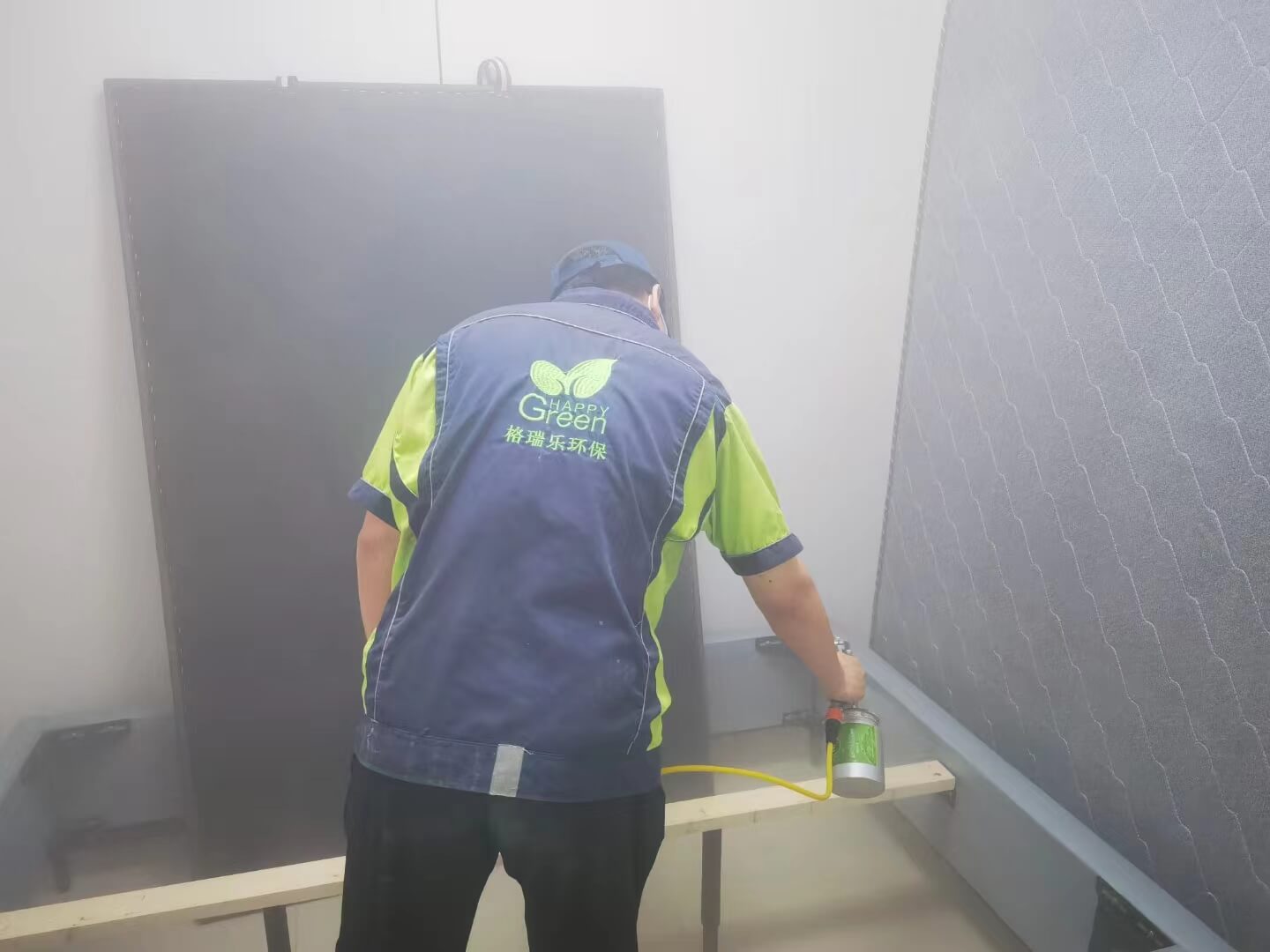 客厅内,工人用擦拭布仔细擦拭电视柜表面,布上蘸有格瑞乐除甲醛清洁液。